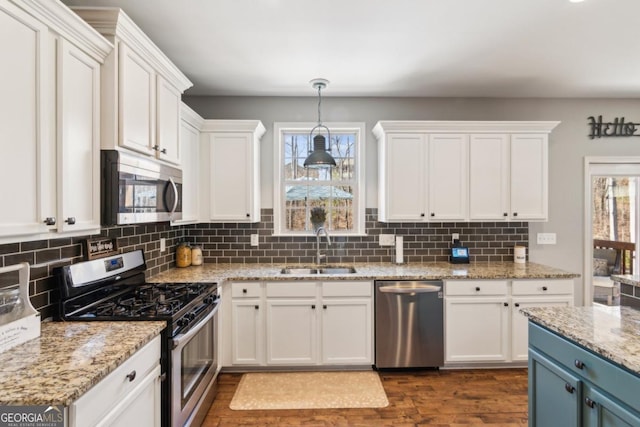 kitchen with blue cabinetry, sink, white cabinetry, appliances with stainless steel finishes, and pendant lighting