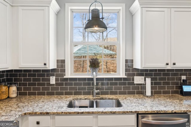 kitchen with dishwasher, white cabinetry, light stone countertops, and sink