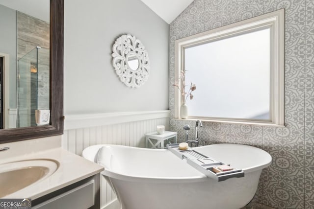 bathroom with a tub to relax in, vanity, and lofted ceiling