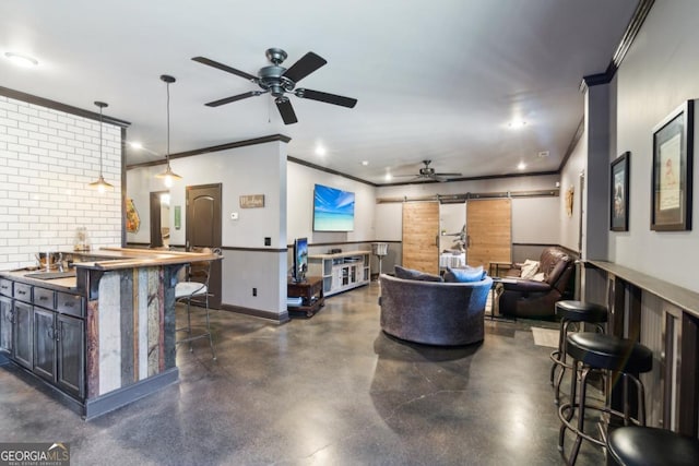 living room featuring sink, ornamental molding, a barn door, and ceiling fan