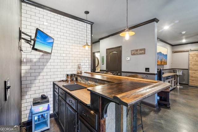 kitchen featuring a barn door, ornamental molding, decorative light fixtures, and a breakfast bar area