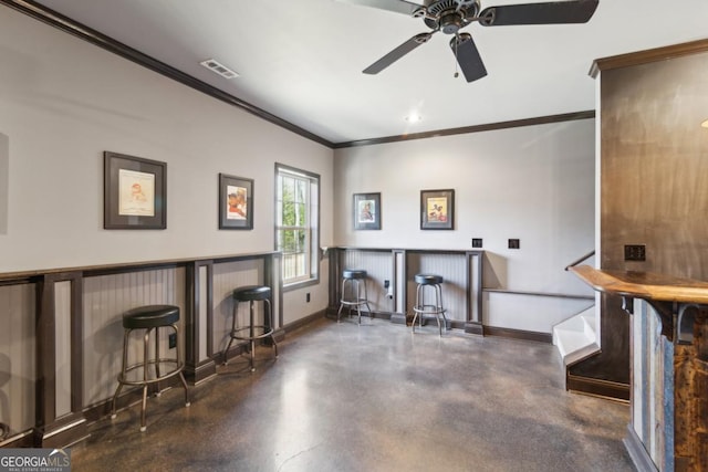 interior space with ceiling fan, ornamental molding, and bar