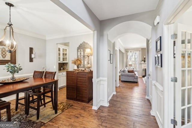 dining room featuring dark wood-type flooring, ornamental molding, and a chandelier