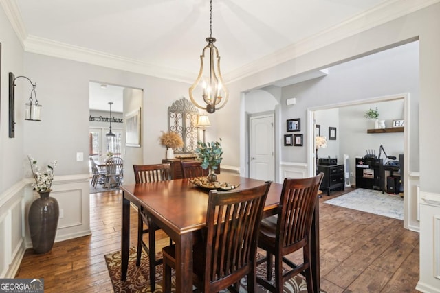 dining area with dark hardwood / wood-style flooring, crown molding, and an inviting chandelier