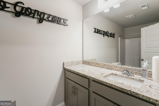 bathroom with vanity, walk in shower, and toilet