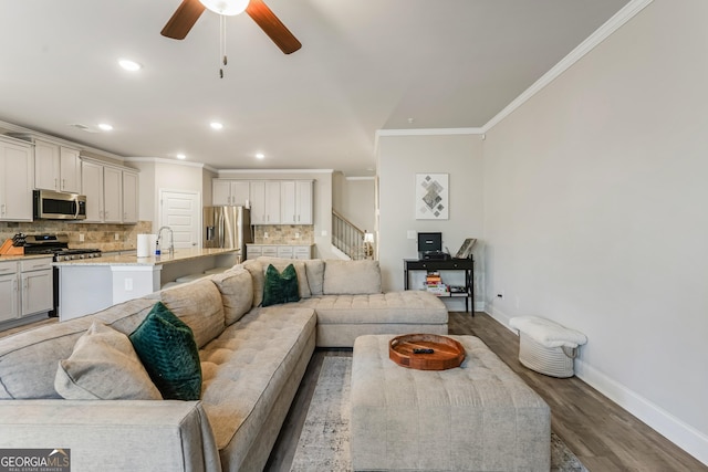 living room with crown molding, sink, ceiling fan, and dark hardwood / wood-style flooring