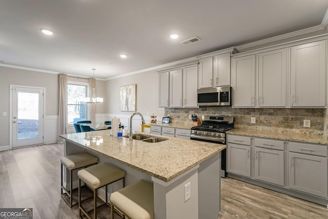 kitchen featuring a kitchen island with sink, sink, gray cabinets, and stainless steel appliances