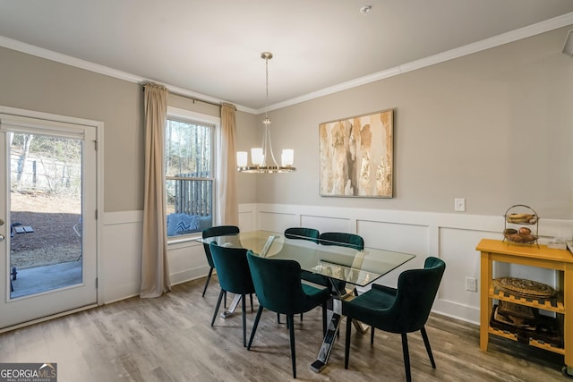 dining area with ornamental molding, hardwood / wood-style floors, and a notable chandelier