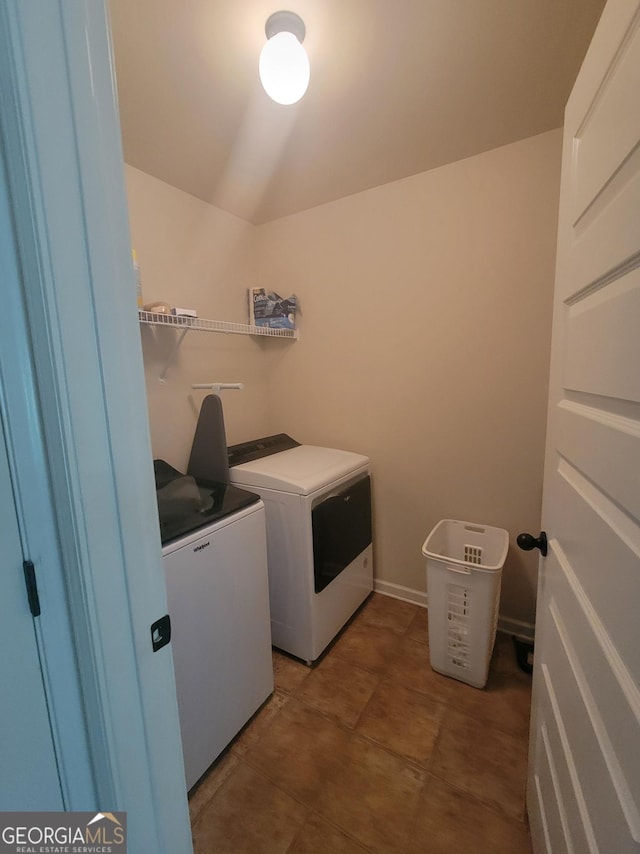 laundry area featuring washer and dryer and dark tile patterned flooring