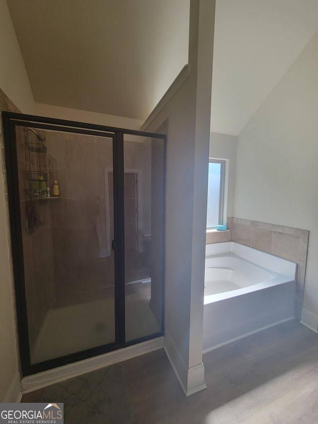 bathroom with hardwood / wood-style floors, vaulted ceiling, and separate shower and tub