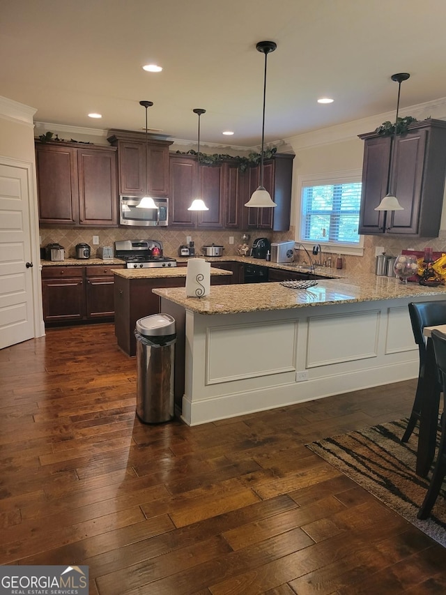 kitchen featuring light stone counters, decorative light fixtures, dark brown cabinets, and appliances with stainless steel finishes