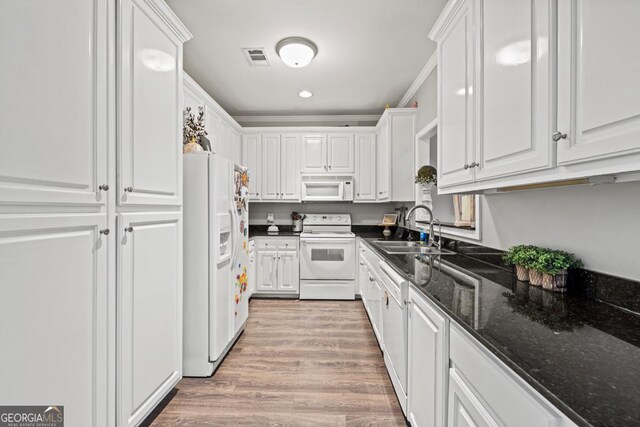 kitchen with sink, white appliances, light hardwood / wood-style flooring, dark stone countertops, and white cabinets