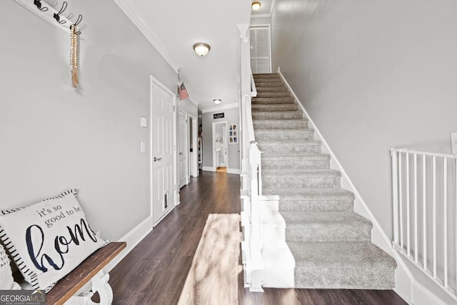 stairs with baseboards, wood finished floors, and ornamental molding