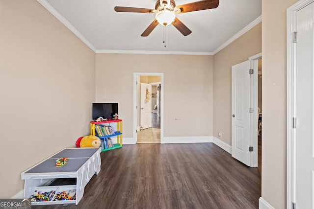 rec room featuring dark wood-type flooring, a ceiling fan, baseboards, and ornamental molding