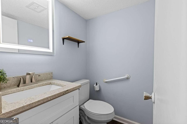 bathroom with vanity, a textured ceiling, and toilet