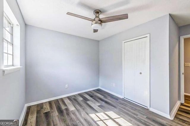 unfurnished bedroom featuring dark wood-type flooring, a closet, and ceiling fan