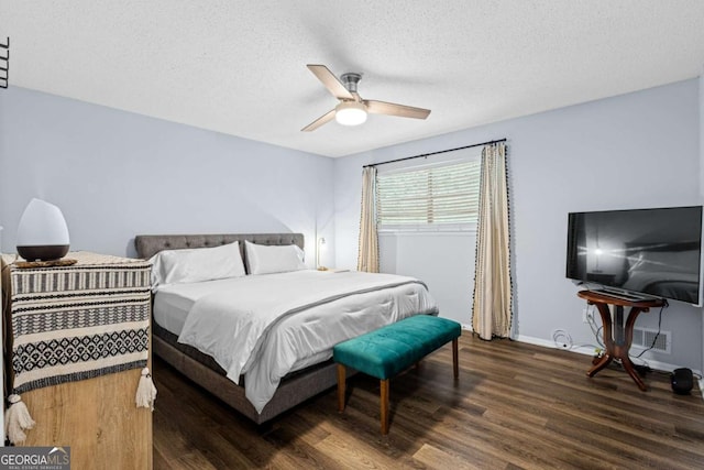 bedroom with ceiling fan, dark hardwood / wood-style flooring, and a textured ceiling