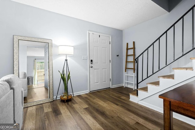 foyer entrance with dark hardwood / wood-style floors and a textured ceiling