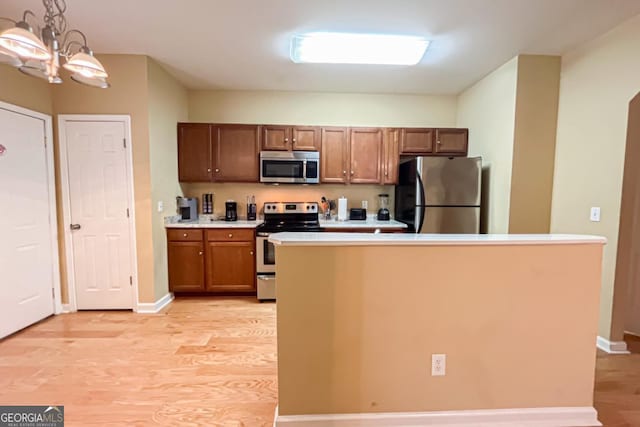 kitchen with pendant lighting, stainless steel appliances, and light hardwood / wood-style flooring