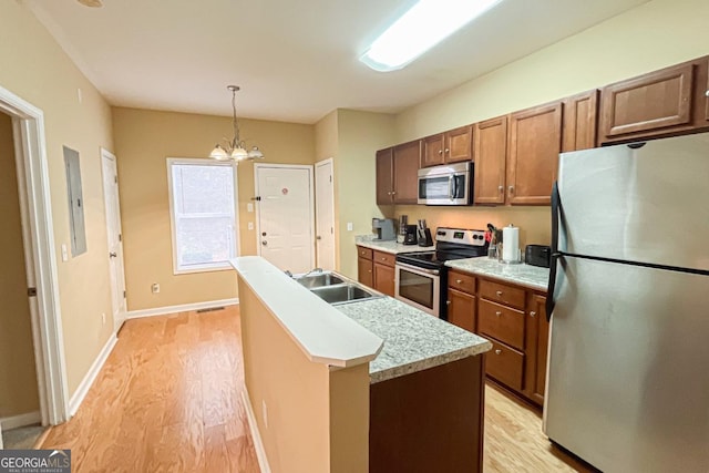 kitchen featuring an island with sink, appliances with stainless steel finishes, pendant lighting, and light wood-type flooring