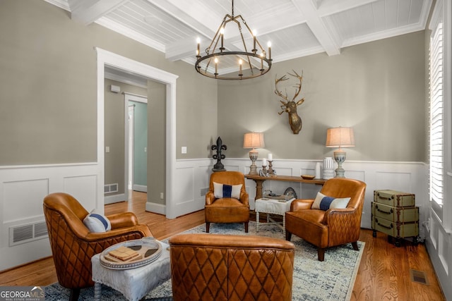 living area with hardwood / wood-style flooring, ornamental molding, a chandelier, and beam ceiling