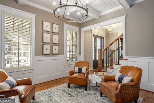 sitting room featuring an inviting chandelier, ornamental molding, wood-type flooring, and beam ceiling