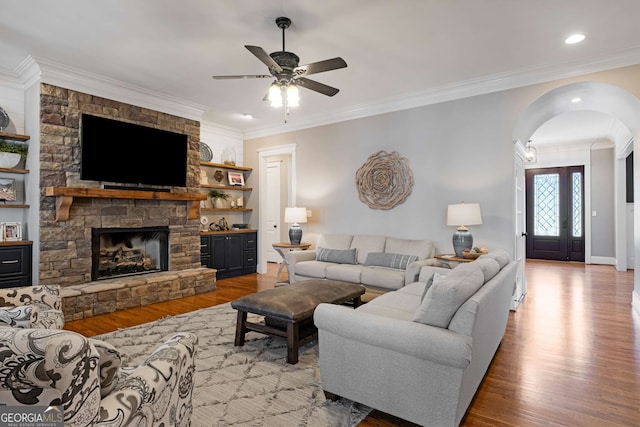 living room with crown molding, a fireplace, light hardwood / wood-style floors, and ceiling fan