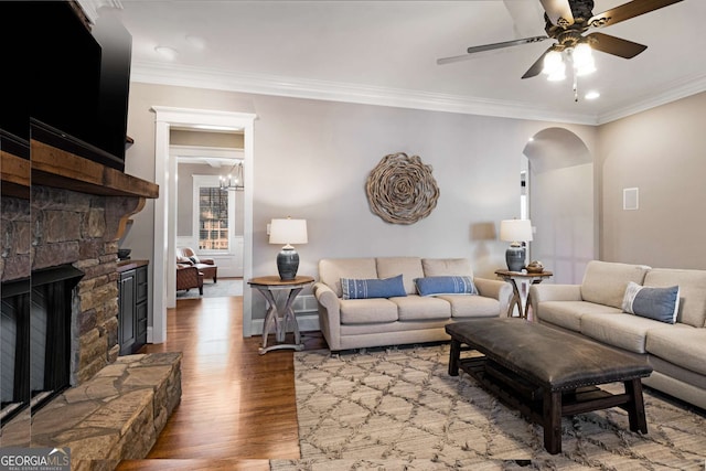 living room featuring hardwood / wood-style flooring, ceiling fan, ornamental molding, and a fireplace