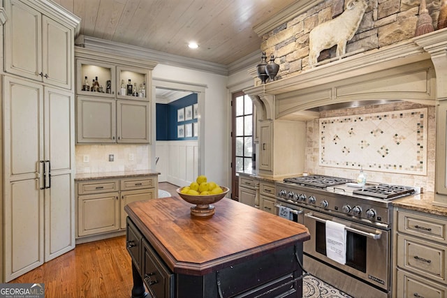 kitchen with crown molding, light hardwood / wood-style flooring, light stone counters, wooden ceiling, and range with two ovens