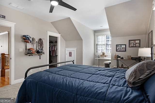 bedroom with a spacious closet, vaulted ceiling, carpet floors, a closet, and ceiling fan