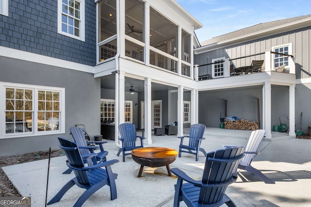 view of patio / terrace featuring a fire pit, a sunroom, and ceiling fan