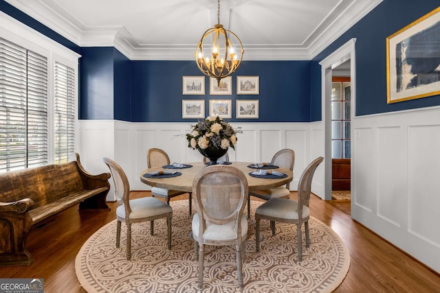 dining room featuring wood-type flooring, ornamental molding, and a chandelier