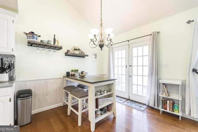 dining area with vaulted ceiling, an inviting chandelier, dark hardwood / wood-style flooring, and french doors