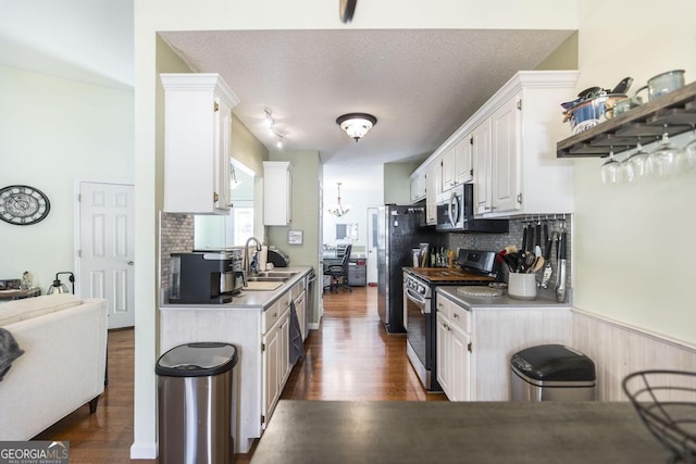 kitchen with sink, white cabinetry, stainless steel appliances, dark hardwood / wood-style flooring, and a chandelier