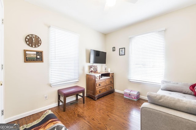 living room featuring dark wood-type flooring and ceiling fan