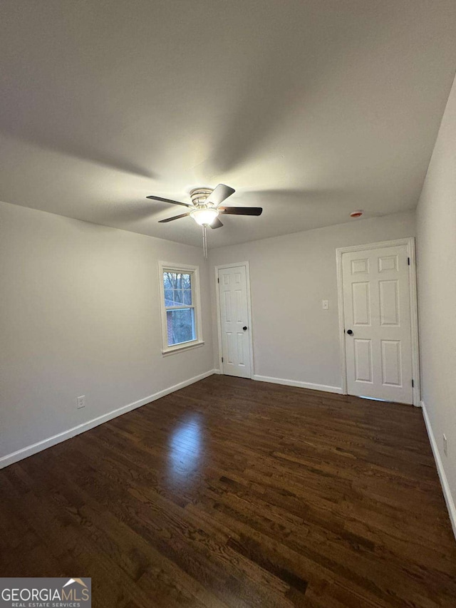 spare room with dark hardwood / wood-style flooring and ceiling fan