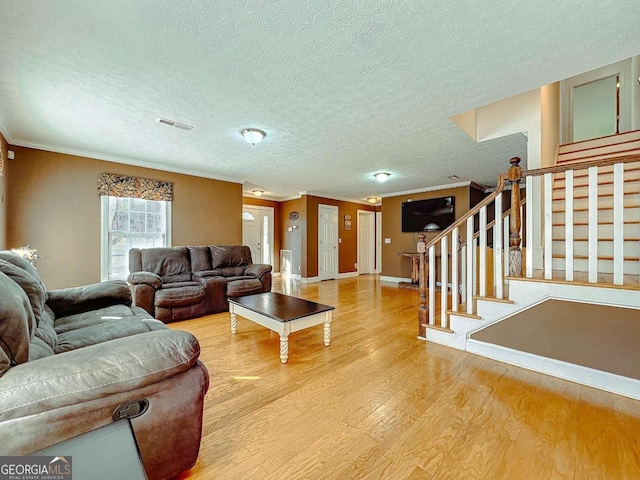 living room featuring wood-type flooring, ornamental molding, and a textured ceiling