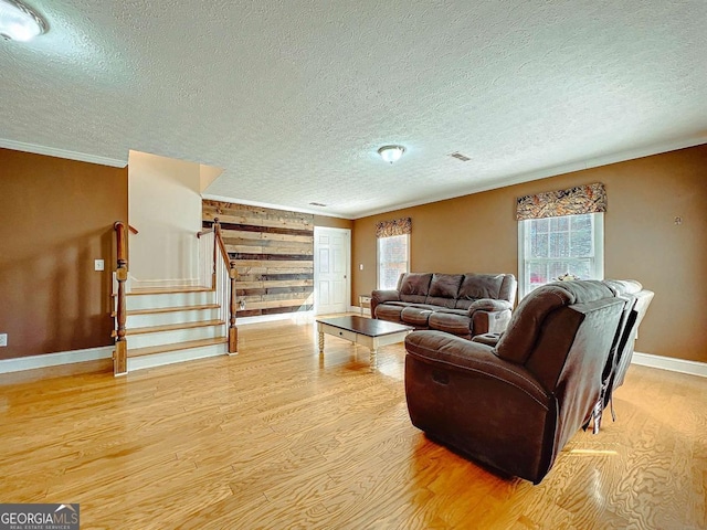 living room with ornamental molding, a textured ceiling, and light hardwood / wood-style flooring