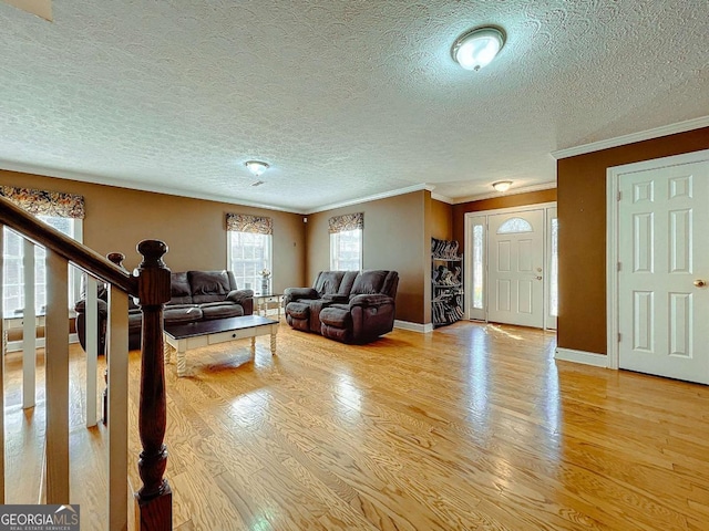 living room with ornamental molding, a textured ceiling, and light wood-type flooring