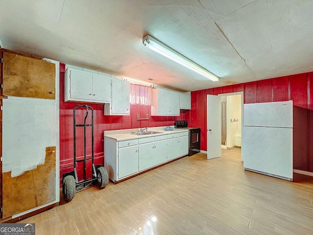 kitchen with black range with electric stovetop, white fridge, sink, and light hardwood / wood-style floors