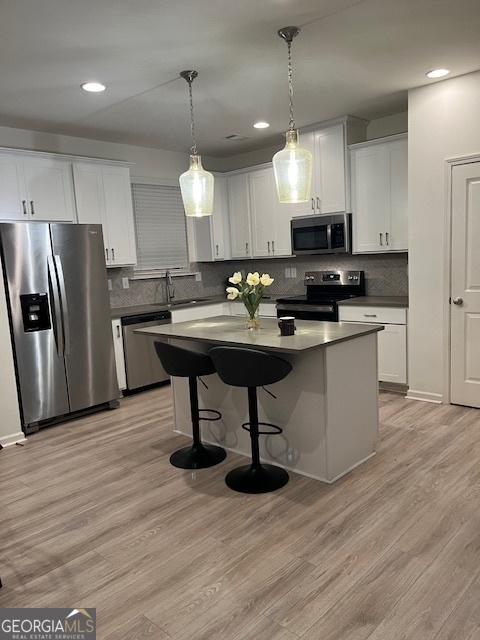 kitchen with white cabinetry, decorative light fixtures, and stainless steel appliances