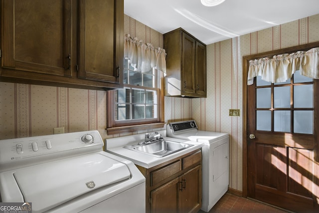 laundry area featuring a sink, wallpapered walls, cabinet space, and washer and dryer