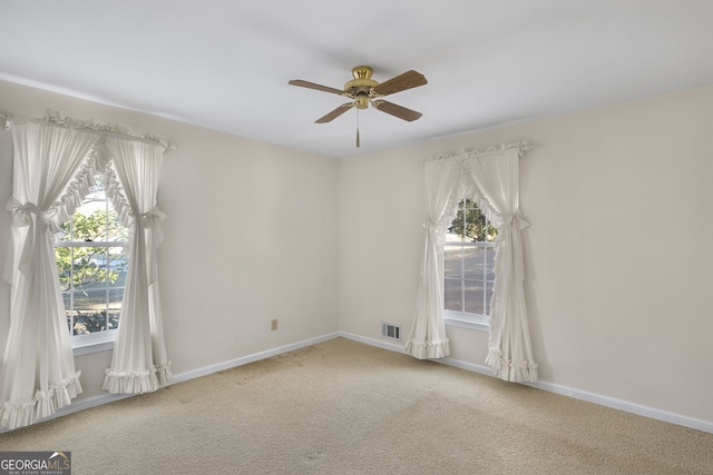 carpeted spare room with ceiling fan, visible vents, and baseboards