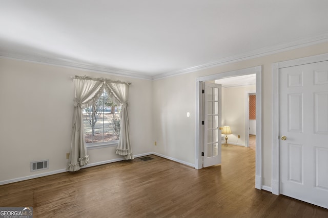 spare room with crown molding, visible vents, dark wood finished floors, and baseboards