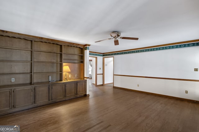 unfurnished living room with dark wood-style floors, a ceiling fan, baseboards, and crown molding