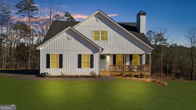 back house at dusk featuring a yard and a porch