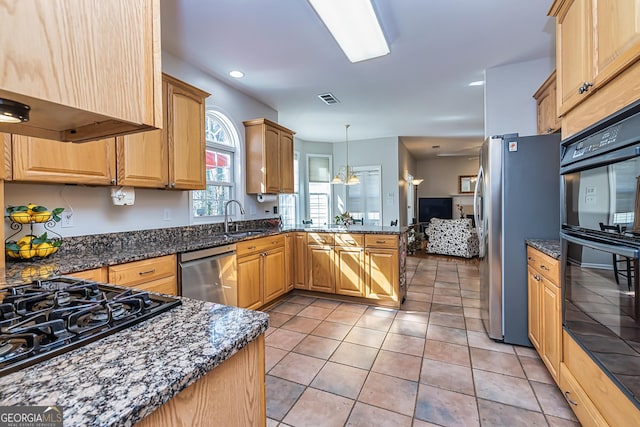 kitchen featuring wall chimney range hood, sink, hanging light fixtures, black appliances, and light tile patterned flooring