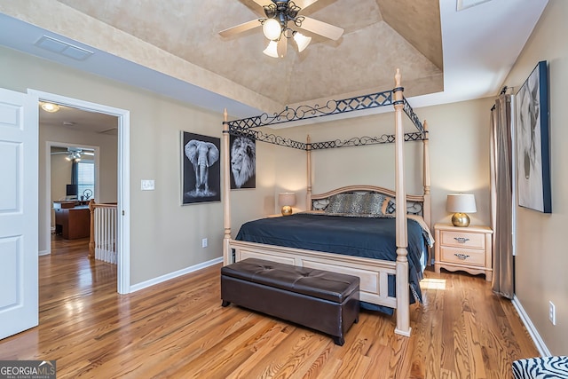 bedroom with a raised ceiling and light wood-type flooring