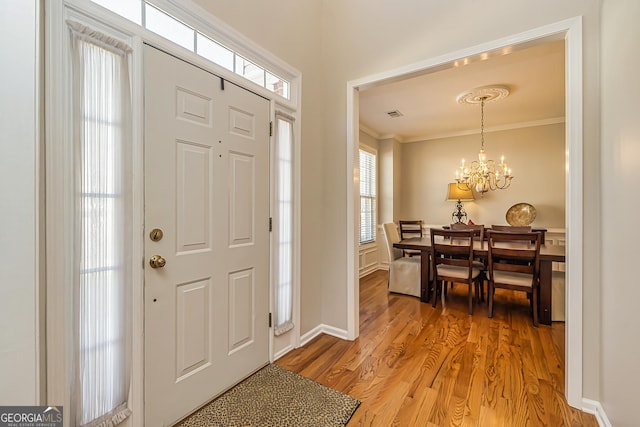 foyer with crown molding, hardwood / wood-style floors, and a notable chandelier