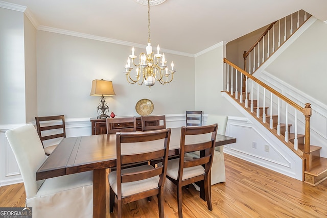 dining area featuring a notable chandelier, ornamental molding, and light wood-type flooring